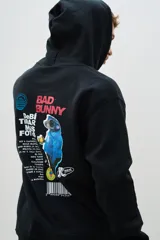 Buzo canguro negro con capucha y cordones ajustables. Estampado en la espalda con la imagen de un personaje de caricatura y el texto "Bad Bunny".