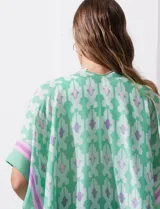 Kimono tejido con estampado abstracto en tonos azules, blancos y violetas. Tiene terminación de ruedo con borlas.