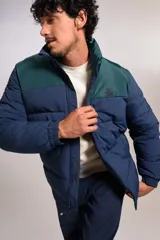 Campera puffer con diseño bicolor, cuerpo en azul marino y canesú superior en verde oscuro. Presenta cuello alto, cierre frontal completo y puños elásticos.