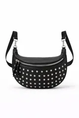 Cartera tipo bandolera de diseño semicircular, confeccionada en cuero sintético negro con tachas metálicas plateadas distribuidas por toda la superficie frontal. Cuenta con cierre superior metálico y correa ajustable.