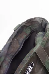 Bolso tote de tela con estampado de camuflaje en tonos verdes y marrones. Tiene asas de hombro y un logo ovalado con letras blancas en el centro.