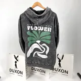 Canguro gris con efecto lavado, corte oversize y estampa en el frente con la frase "Growing Like a Flower" y un diseño de una flor en verde y blanco.