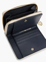 Billetera Tommy Hilfiger color crema con cierre de cremallera y logo TH dorado en el frente.