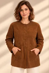 Camisa de cuero color marrón, de corte recto y largo medio, con cuello redondo a la base, cierre frontal con broches metálicos y bolsillos aplicados en los laterales.