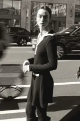Vestido corto de tejido suave, color negro con detalles en blanco. Presenta cuello solapa, escote en pico, manga larga, falsos bolsillos delanteros y cierre frontal con botones dorados.