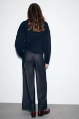 Pantalón de jean tiro medio con corte culotte, pernera ancha y corta. Presenta bolsillos delanteros de plastrón, costuras decorativas verticales y cierre frontal con cremallera y botón.