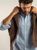 Camisa de corte regular confeccionada en tejido Oxford de algodón, con diseño de rayas verticales en tonos azul y blanco. Presenta cuello abotonado, cierre frontal con botones y un bolsillo en el pecho con logo bordado.