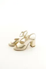 Sandalias de taco grueso y plataforma delantera, confeccionadas en cuero vacuno color dorado con tira en la parte frontal y correa ajustable al tobillo.