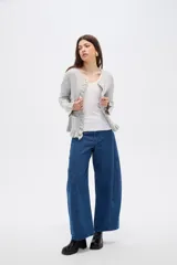 Saco de punto color gris, con cuello redondo, cierre frontal con botones y detalle de volados en la tapeta y el ruedo. Presenta mangas largas con puños acampanados.