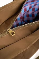 Bolso tipo tote bag color marrón con diseño capitonado de ondas, asas largas y placa metálica con el logo de la marca.