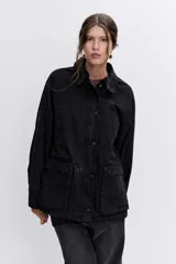 Campera de denim negro con cierre frontal y botones a presión, cuello clásico y bolsillos laterales.