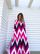 Vestido camisero largo con diseño de estampado chevron en colores fucsia, beige y negro. Presenta cuello camisero, cierre frontal con botones y mangas tres cuartos.