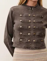 Chaqueta estilo militar de denim color marrón, con cuello redondo, cierre frontal y detalle de botones decorativos en el frente y en los puños.