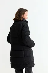 Campera puffer larga de color verde militar, con cuello alto, cierre frontal y diseño acolchado horizontal.