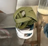 Brazalete ancho de cuero color verde oliva con diseño entrelazado.