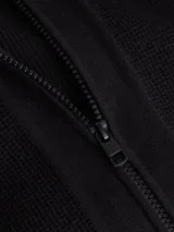 Sweater de punto negro con cuello alto y cierre frontal de cremallera. Presenta un pequeño parche con el logo 'ck' en la manga izquierda.