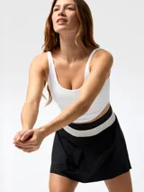Top deportivo blanco con costuras visibles tipo corseteras en el pecho, tirantes delgados y espalda rebajada.