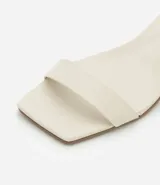 Sandalias negras de cuero sintético, con punta cuadrada, tira fina sobre los dedos, pulsera con hebilla al tobillo y tacón geométrico bajo.