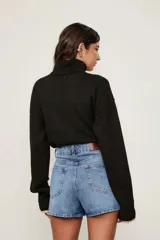 Pollera short de denim azul con diseño cruzado, tiro medio y bajo redondeado.