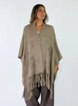 Ruana gris de tejido punto con detalles en relieve y flecos en el ruedo.