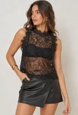 Top negro sin mangas, confeccionado en encaje transparente con cuello alto y detalles de volados sutiles en los bordes.