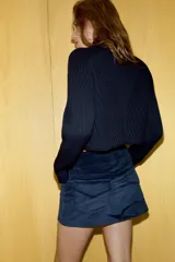 Falda mini de tiro bajo confeccionada en pana, con cintura con trabillas, bolsillos laterales y cierre frontal con cremallera y botones metálicos dorados.