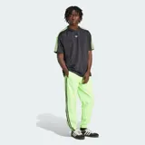 Remera de corte holgado Adidas Adicolor Jacquard, color negro con detalles en verde lima brillante en el logo del pecho y las clásicas tres tiras en los hombros y mangas. Presenta un sutil diseño de rayas verticales tipo jacquard.