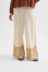 Pantalon ancho de algodón en color beige con detalle de bordado decorativo en el ruedo.