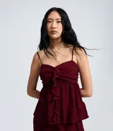 Blusa tipo bata color bordó, confeccionada en crepé, con breteles finos ajustables, busto fruncido y detalle de volado vertical en el frente. Posee espalda con lastex para un mejor ajuste.