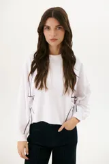 Buzo negro de corte cropped con mangas largas abullonadas y costuras a la vista en color blanco.