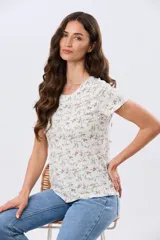 Remera de manga corta con cuello redondo, confeccionada en algodón con estampa de diseño floral en tonos rosados y verdes sobre base beige.