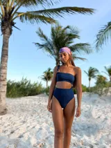 Malla enteriza azul brillante con diseño asimétrico de un solo hombro, aberturas laterales con aros de madera y bombacha tiro alto.