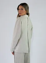 Blazer de lino color marrón con solapa clásica, cierre frontal de tres botones, bolsillos aplicados con solapa y costuras pespunteadas en contraste.