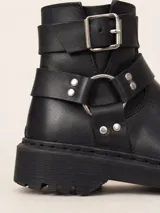 Botas de caña baja confeccionadas en cuero vacuno encerado color negro. Presentan un diseño con hebillas metálicas niqueladas en la caña y una tira decorativa con herrajes en el tobillo. Cuentan con cierre lateral, suela de goma negra con plataforma y forro interior de cuero vacuno.