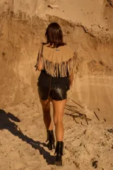 Chall de gamuza natural con diseño de flecos largos en todo el borde y detalle de pins metálicos decorativos en la parte frontal.