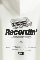 Canguro blanco de mezcla de algodón con interior cepillado suave y estampado frontal negro con la palabra "Recordin'". Tiene capucha de doble capa con cordón ajustable, hombros caídos, bolsillo canguro y puños y bajo acanalados. Corte holgado.