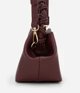 Bolso de mano pequeño color borgoña, con cuerpo de forma trapezoidal y asas cortas trenzadas. El material parece ser cuero sintético (PU).