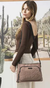 Bandolera de diseño práctico y moderno, confeccionada en tela impermeable color verde militar. Presenta un bolsillo frontal con diseño capitoneado geométrico, cierre principal y bolsillo trasero con cierre. Incluye correa ajustable y detalles en negro.
