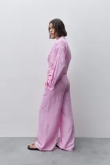 Pantalón de tiro alto con silueta amplia y caída fluida, confeccionado en tejido celeste con textura a rayas finas. Cuenta con cintura elástica con lazo de ajuste y bolsillos laterales.