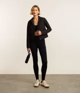 Campera deportiva negra con cuello alto, cierre frontal con cremallera y bolsillos laterales. Presenta un recorte en la espalda.