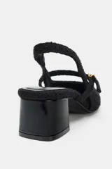 Zapato destalonado de tejido texturizado color negro, con punta cuadrada, tira delantera con hebilla metálica dorada y tacón bloque de acabado brillante.