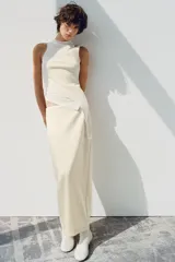 Falda midi recta de tiro medio confeccionada en tejido satinado color beige, con abertura en la espalda y cierre lateral con cremallera oculta.