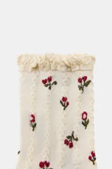 Calcetines marrones con estampado de flores en tonos naranja y beige, confeccionados en hilatura de algodón. Presentan un detalle de tejido con estructura y acabado con puntilla a tono en el borde superior.