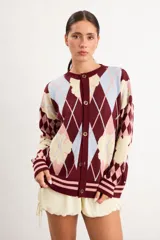 Saco liviano de punto oversize con diseño de rombos argyle y flores superpuestas en tonos bordó, celeste, beige y rosa. Presenta escote redondo, cierre frontal con botones y puños y ruedo acanalados.