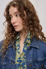 Chaleco oversize de jean negro, con cuello camisero, cierre frontal con botones metálicos y bolsillos delanteros.