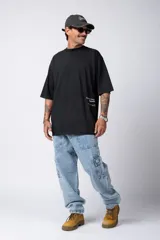 Remera blanca de corte oversize con cuello redondo y mangas cortas. Presenta un pequeño estampado tipográfico en la parte inferior frontal y un diseño gráfico de mayor tamaño en la espalda.