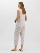 Pijama compuesto por remera sin mangas con escote redondo, botones frontales y detalle de puntilla, acompañado de un pantalón capri con cintura elástica. Presenta un estampado floral en tonos rosados sobre base gris.