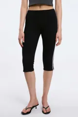 Pantalón capri negro de corte ajustado, con cintura elástica y franjas blancas decorativas en los laterales.