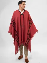 Poncho tejido color ladrillo con diseño geométrico en negro y flecos en el ruedo.