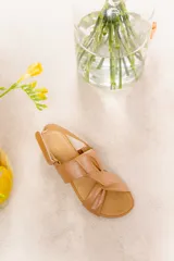 Sandalias de cuero color marrón claro con tiras anchas entrelazadas y suela de goma flexible.